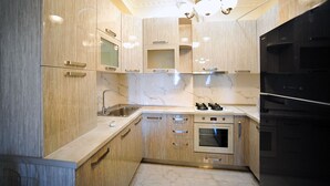 A modern kitchen with light wood cabinets, a stainless steel sink, a gas stove, and a built-in oven. - Apartment on Kostava str. (Tbilisi)