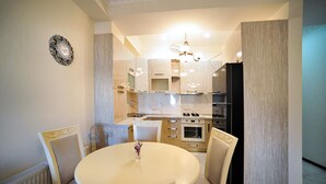 A modern kitchen with a dining area, featuring a round table, chairs, and a chandelier. - Apartment on Kostava str. (Tbilisi)
