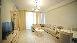 A living room with a TV, sofa, coffee table, and dining area. - Apartment on Kostava str. (Tbilisi)