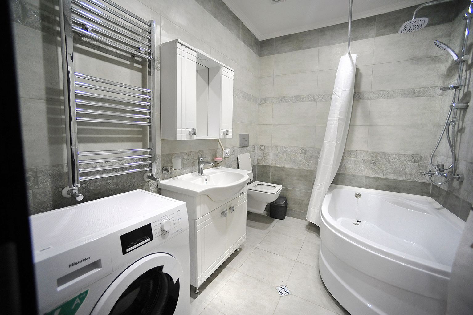 A modern bathroom with a washing machine, sink, toilet, and bathtub.