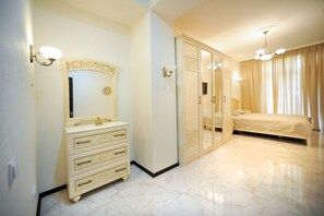 A bedroom with a large wardrobe, a dresser, a bed, and a chandelier. - Apartment on Kostava str. (Tbilisi)