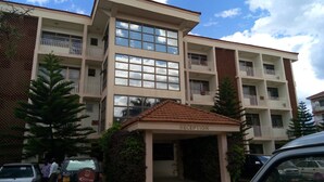 A multi-story hotel with a reception area, balconies, and a parking lot. - Margarita Palace Hotel (Lira)