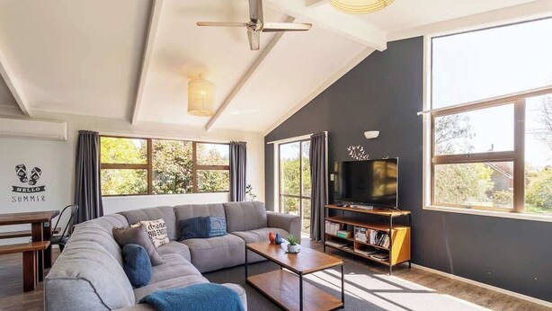 A modern living room with a sectional sofa, a coffee table, a TV, and a bookshelf.