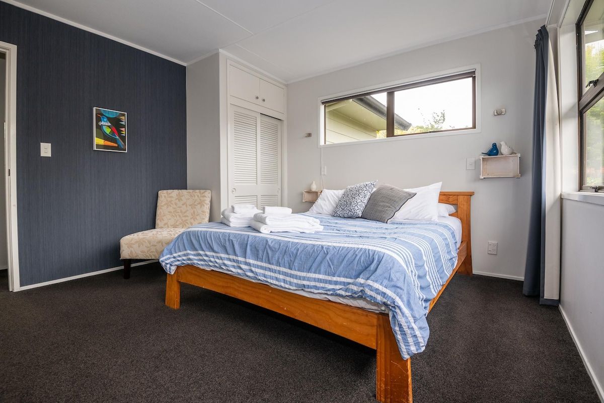 A bedroom with a bed, a chair, a window, and a door.