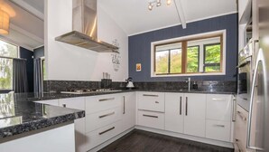 A modern kitchen with white cabinets, dark countertops, and a large window.