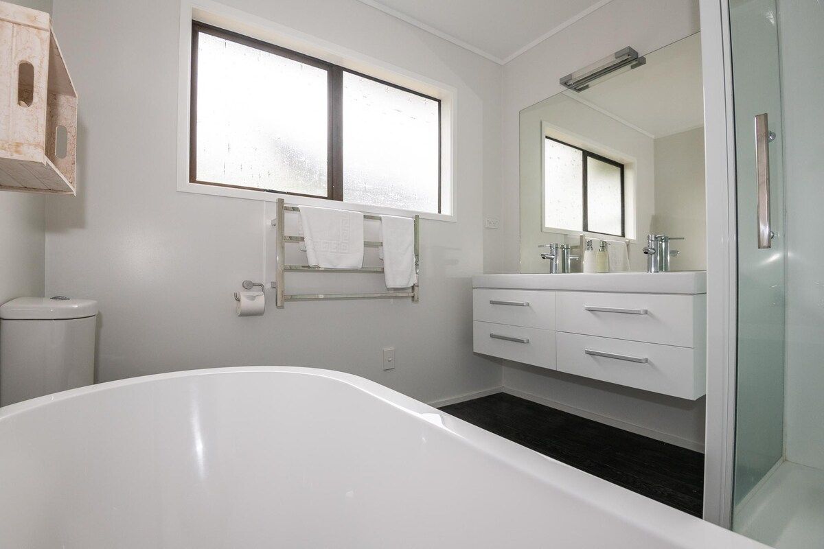A modern bathroom with a freestanding bathtub, a large mirror, and a glass shower enclosure.