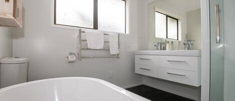 A modern bathroom with a freestanding bathtub, a large mirror, and a glass shower enclosure.