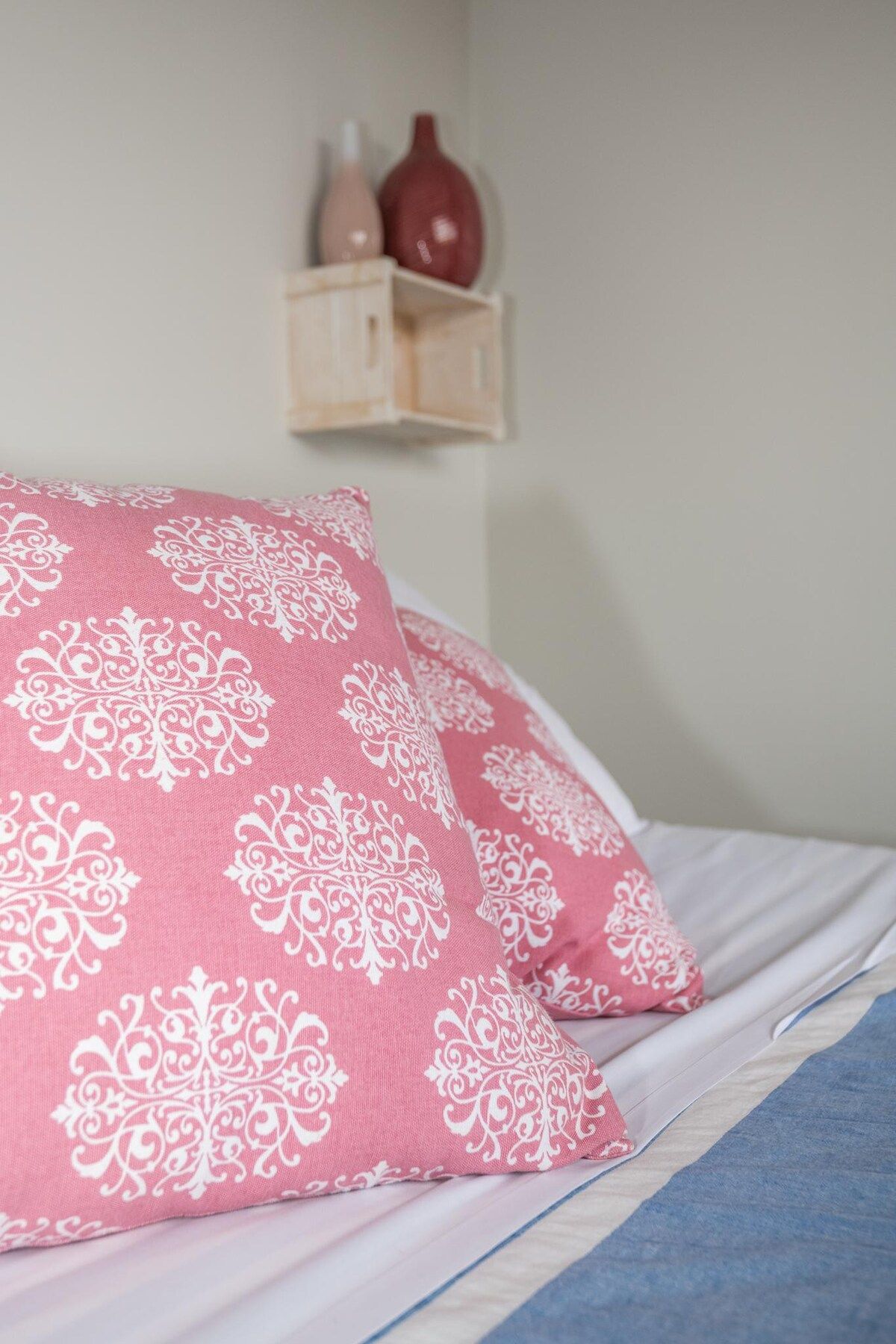 Una cama con almohadas rosas y una manta azul.