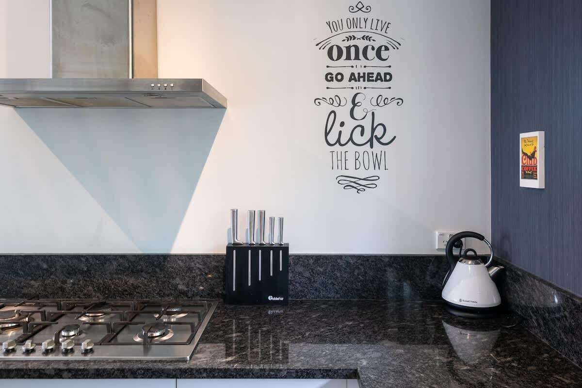 A modern kitchen with a gas stove, a kettle, and a knife block on the counter.