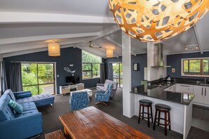 Ein modernes Wohnzimmer mit einer Couch, einem Holztisch und einer Küchenzeile mit einer Bar und Hockern.