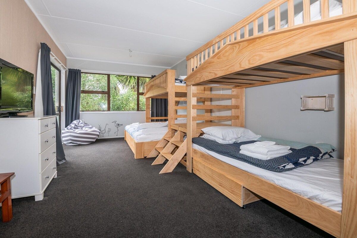 Une chambre avec des lits superposés, un bureau, une chaise et un téléviseur.