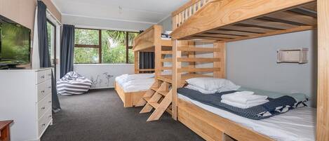 Une chambre avec des lits superposés, un bureau, une chaise et un téléviseur.