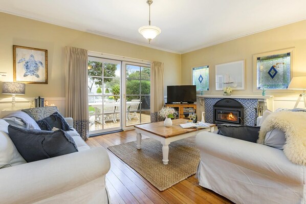 A cozy living room with a fireplace, two sofas, a coffee table, and a TV.