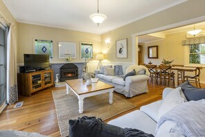 A living room with a fireplace, sofa, coffee table, and a television on a wooden cabinet.