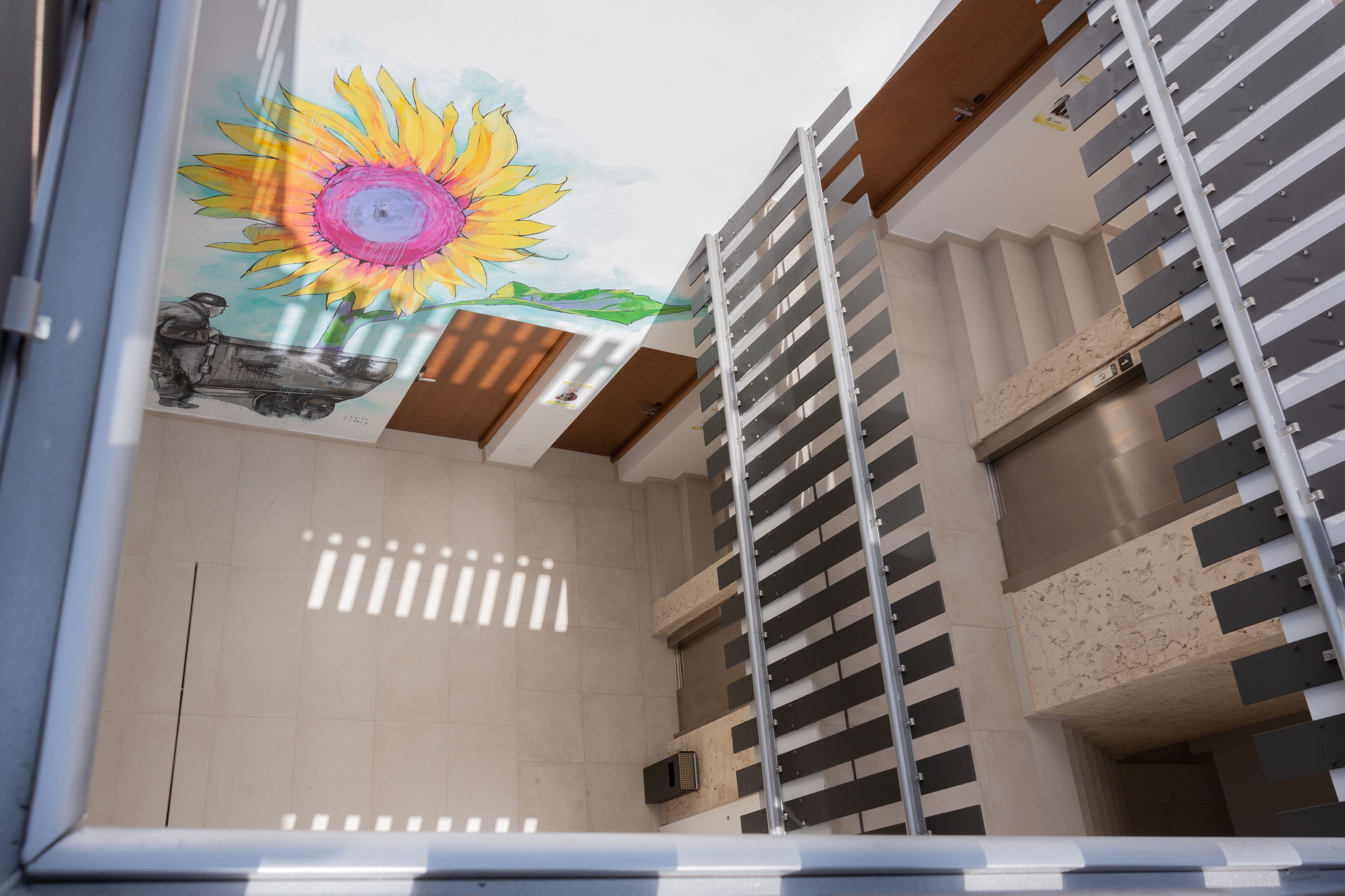 Un interior moderno con un mural de sol, una escalera y vistas al exterior.