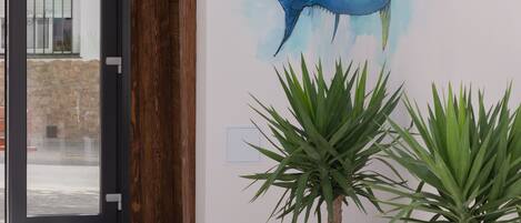 Un intérieur moderne agrémenté d’une grande fresque murale représentant une baleine, de deux plantes en pot et d’une porte vitrée donnant sur l’extérieur.