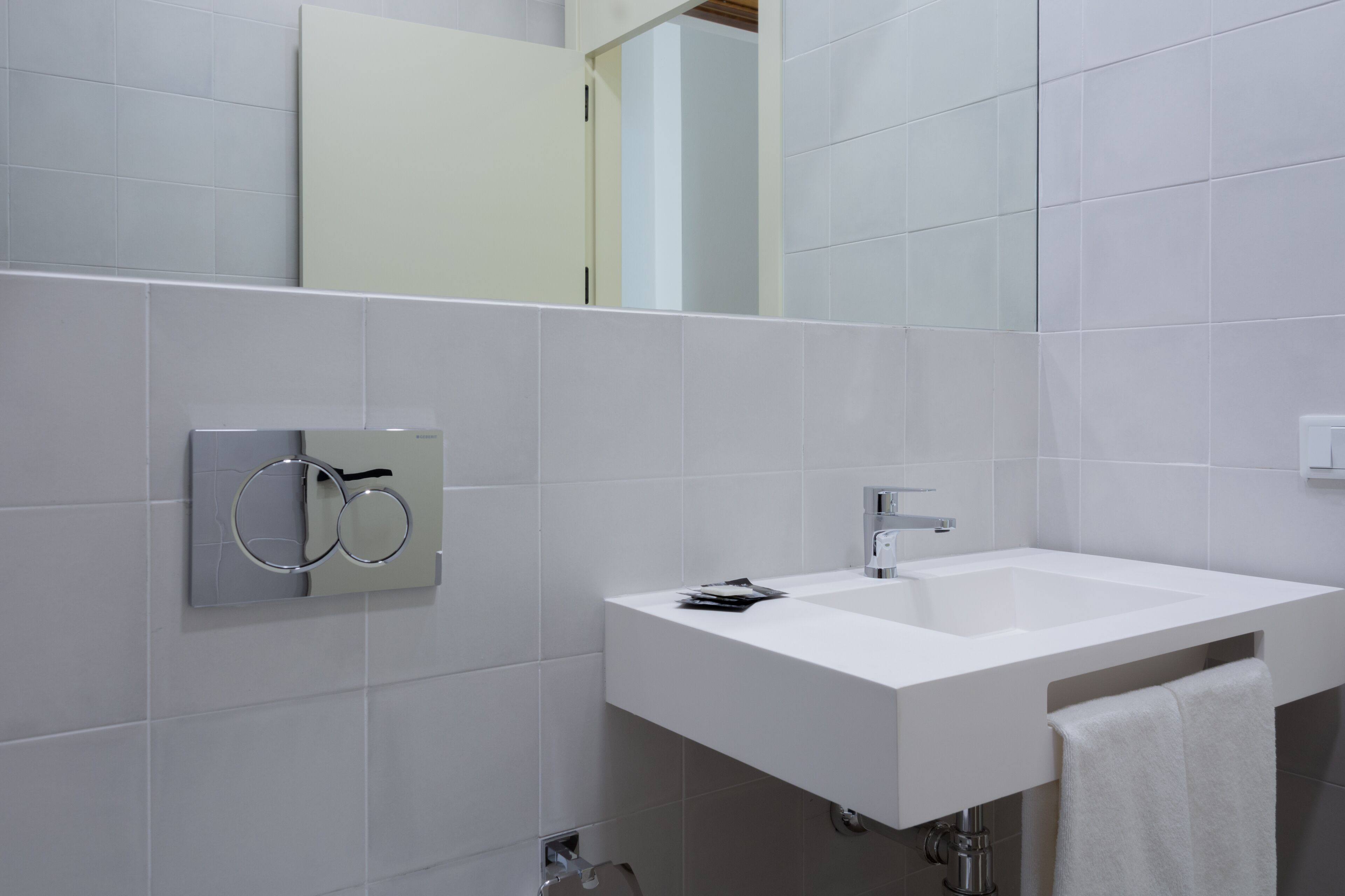 Un baño moderno con lavamanos, espejo y toallero blancos.