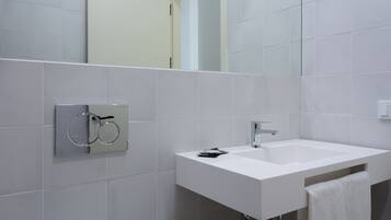 Un baño moderno con lavamanos, espejo y toallero blancos.