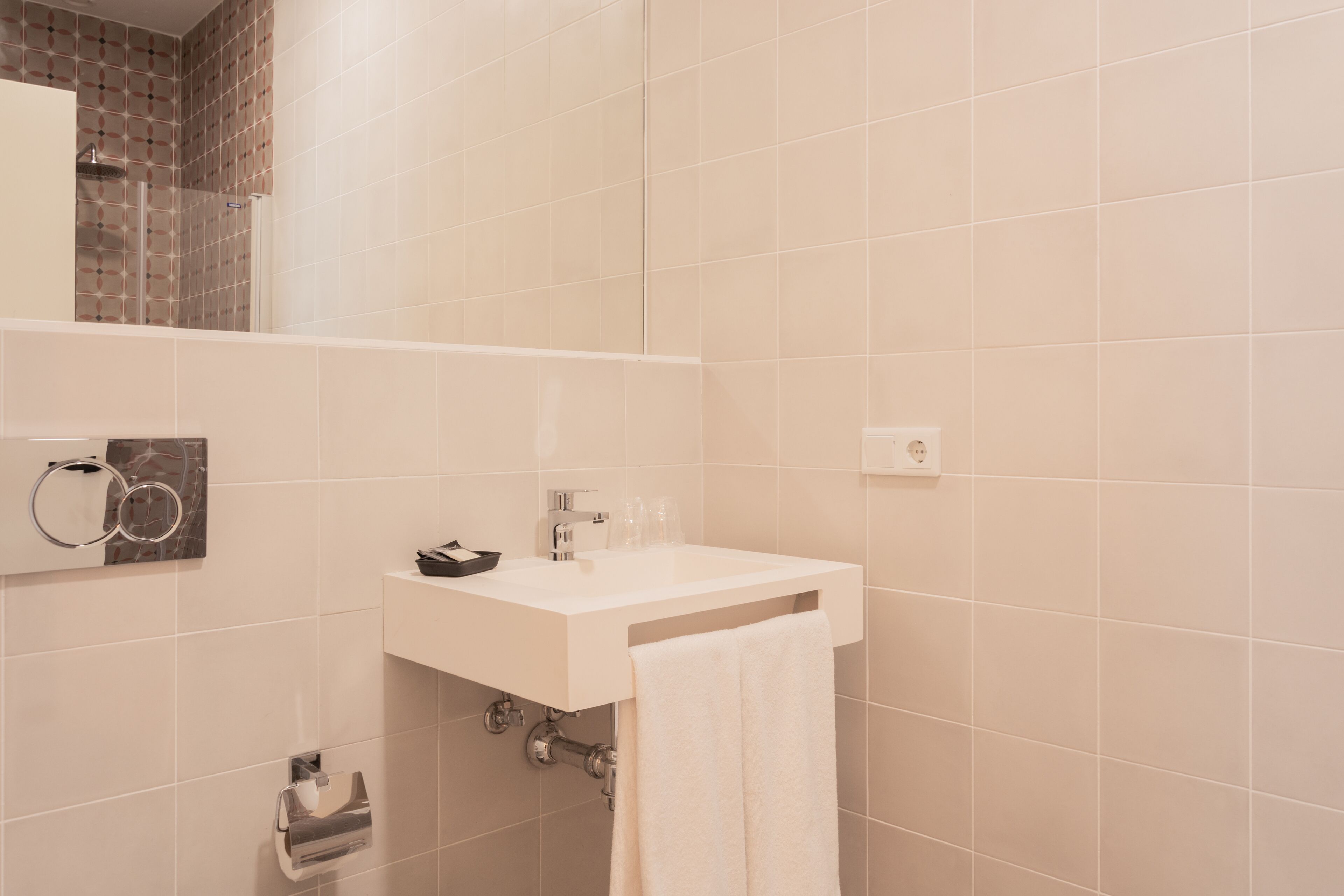 A bathroom with a white sink, a towel hanging on the wall, and a toilet paper holder.