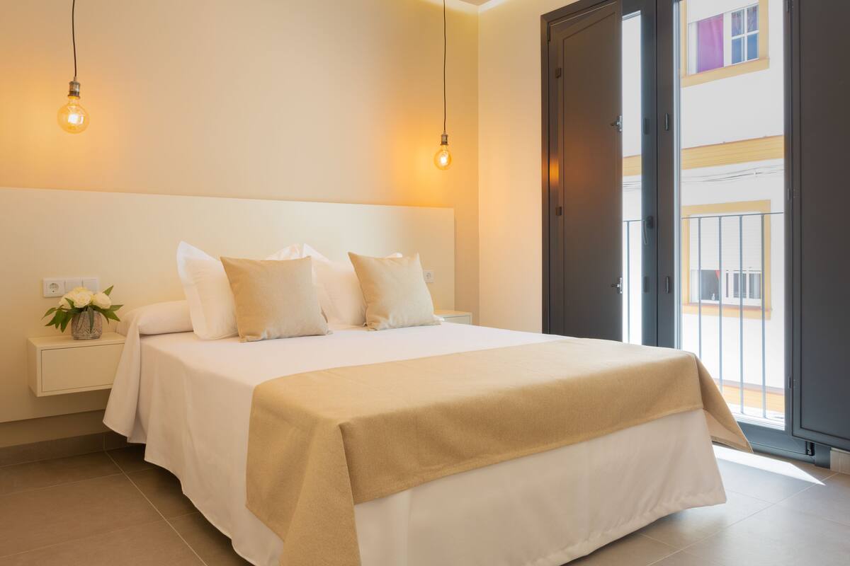 A modern bedroom with a large bed, bedside tables, and a view of the outside.
