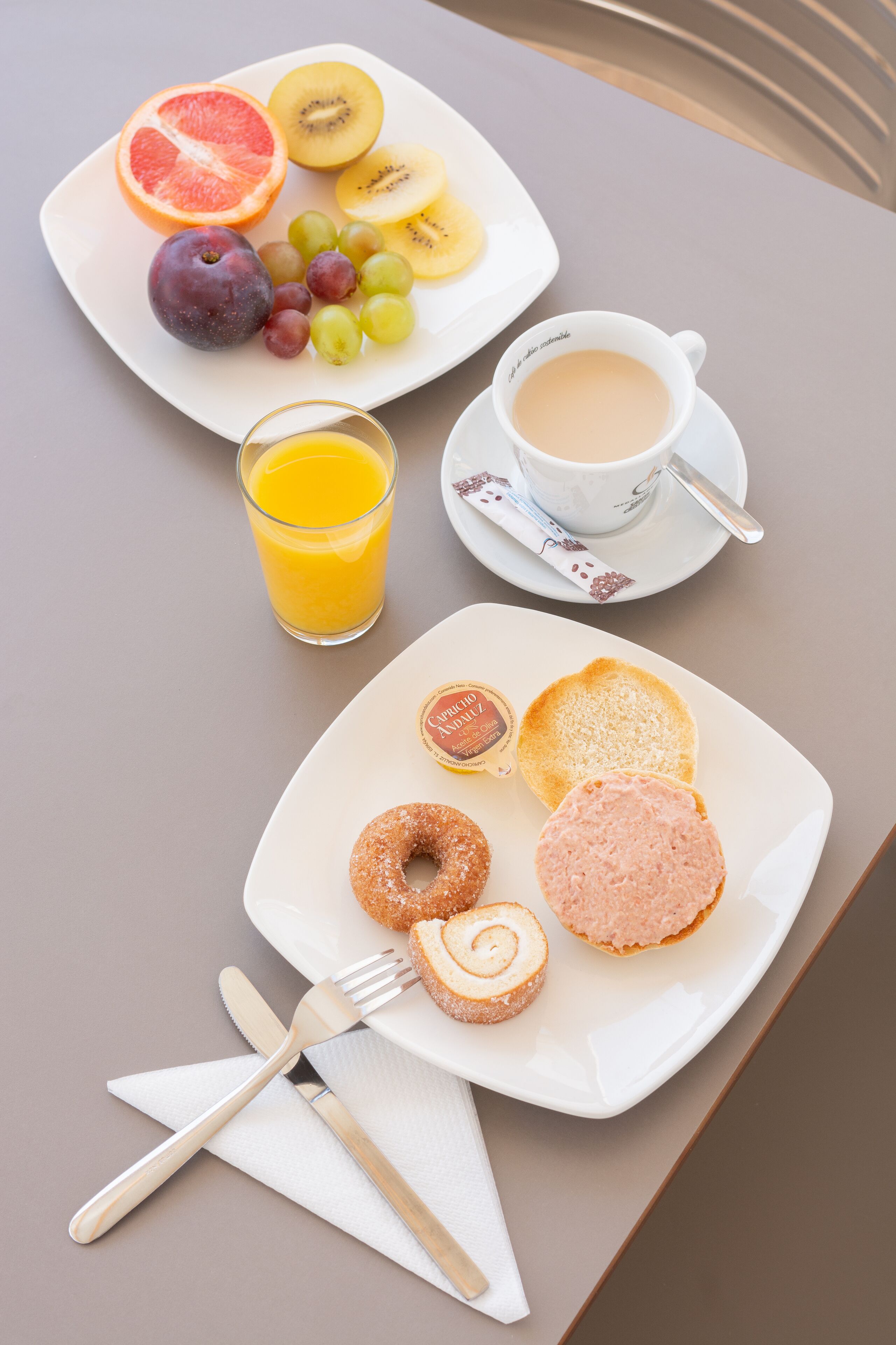 Een ontbijttafel met fruit, gebak en een kop koffie.