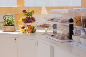 A breakfast buffet with fruits, pastries, and a coffee machine. - Hostal La Mina (Conil de la Frontera)