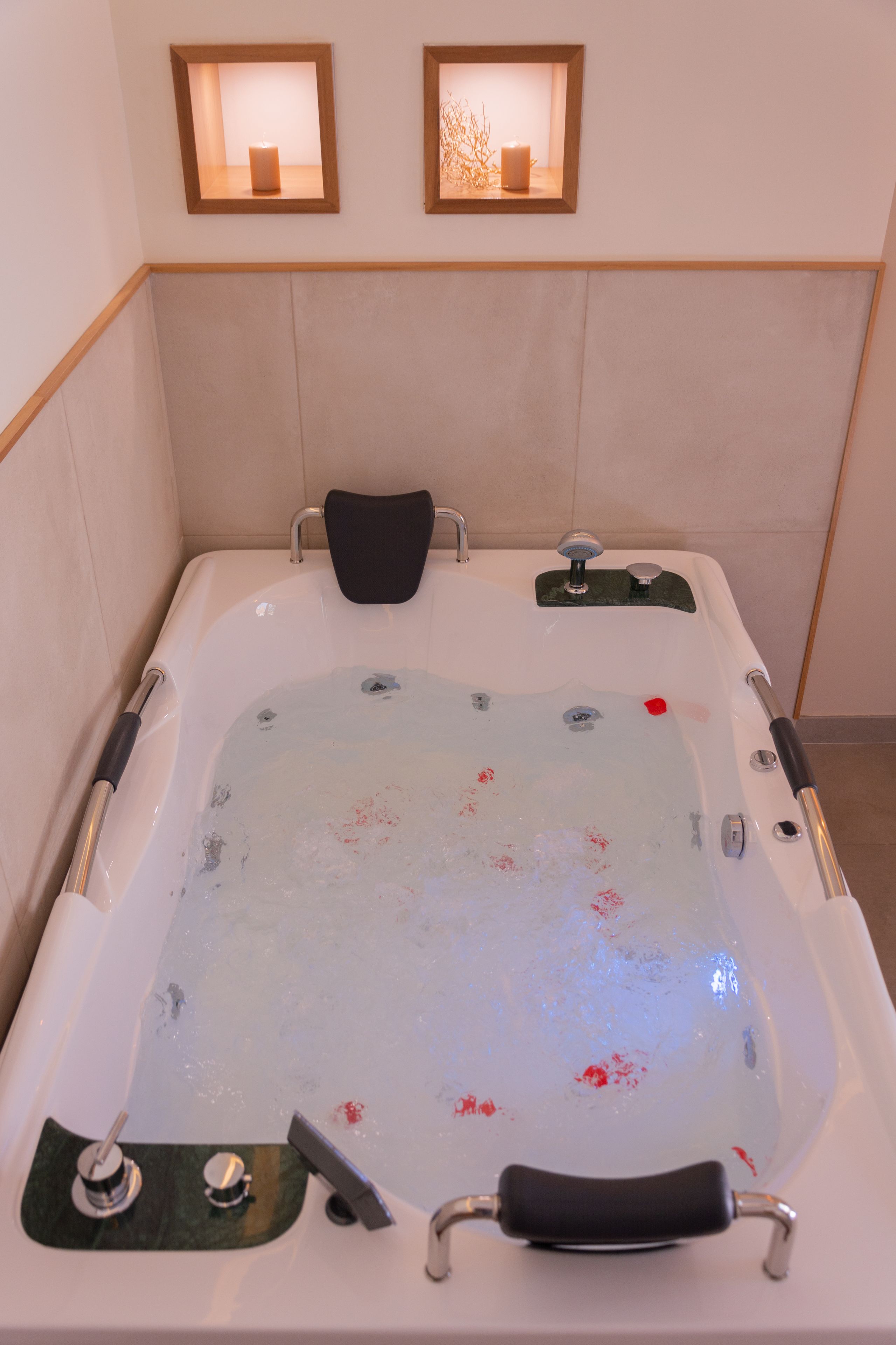 A bathtub with a black seat and a handheld showerhead.