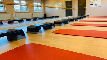 Uma academia com equipamentos de exercício, colchonetes e um espelho.