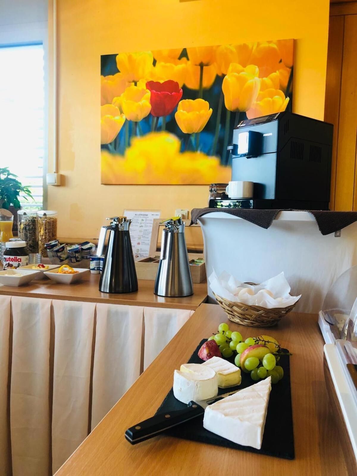 Una mesa de desayuno con queso, uvas y una cafetera.