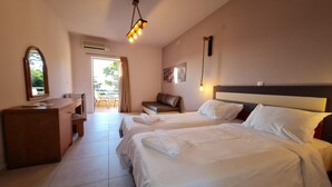 A hotel room with two beds, a desk, a chair, and a balcony. - Dioni Hotel (Rethymno)