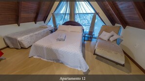 Un dormitorio con una cama grande, dos camas más pequeñas y una silla.