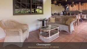 Una habitación acogedora con muebles de mimbre, una mesa de vidrio y un amplio ventanal con vistas a la vegetación.