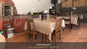 Un comedor acogedor con chimenea de piedra, mesas de madera y una cocina rústica al fondo.