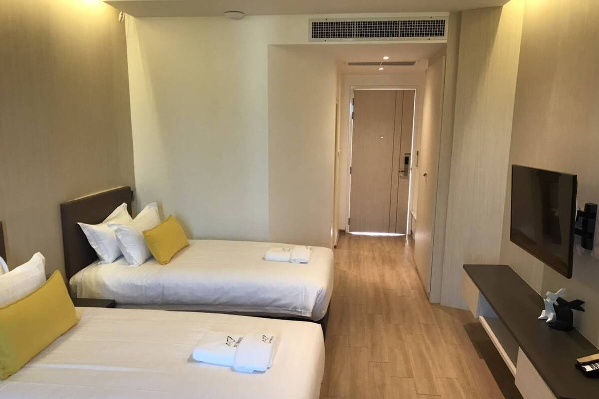 Une chambre d’hôtel avec deux lits, une télévision et un bureau avec un téléphone.