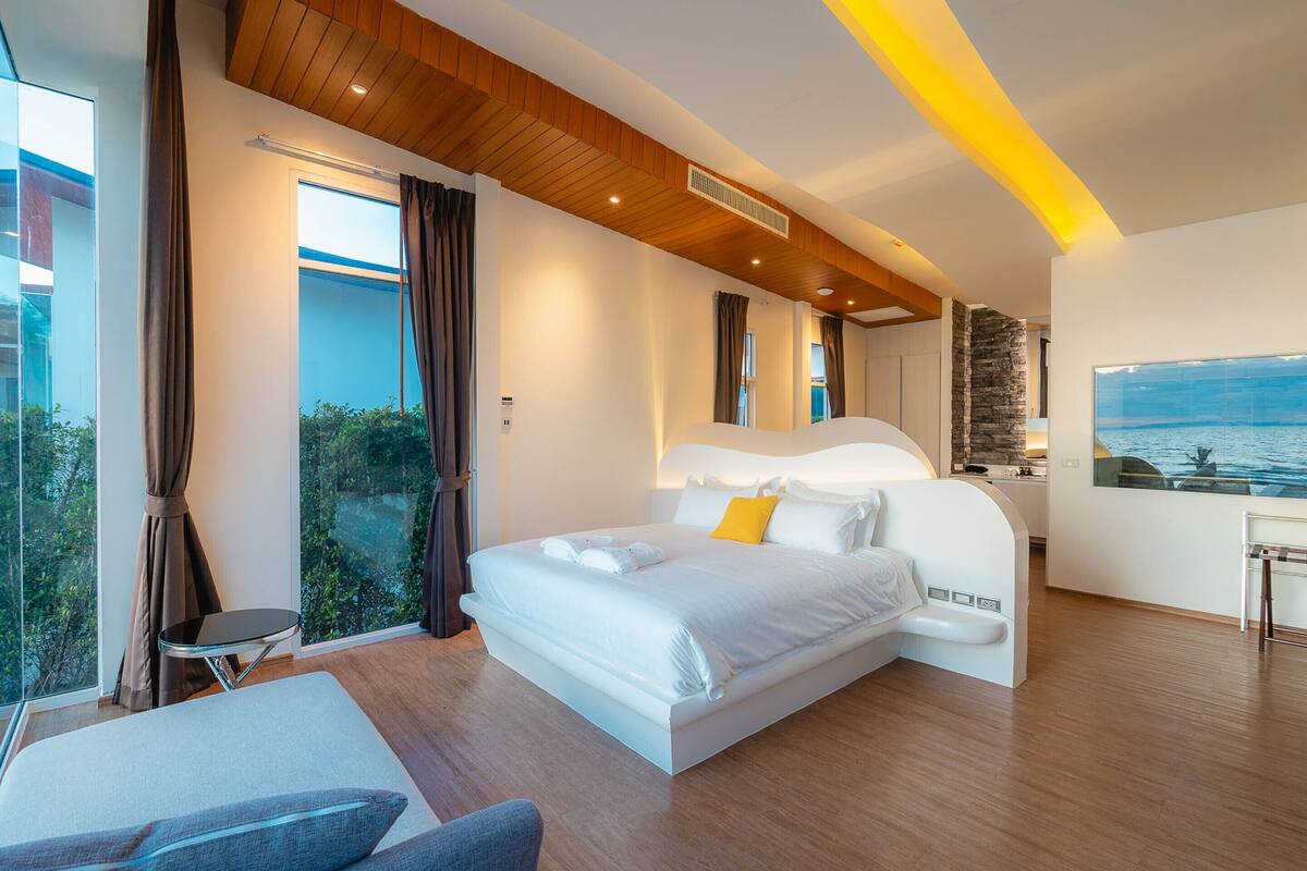 Une chambre d’hôtel moderne dot ée d’un grand lit, d’un coin salon et offrant une vue sur la mer.