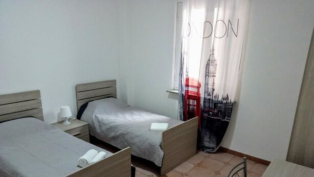 Un dormitorio con dos camas, una ventana con cortina que muestra un monumento de Londres y suelo de baldosas.