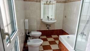 Un baño con inodoro, bidé, lavamanos y bañera.
