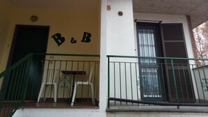 Un edificio con un letrero de hospedaje, una escalera y una ventana con persianas.