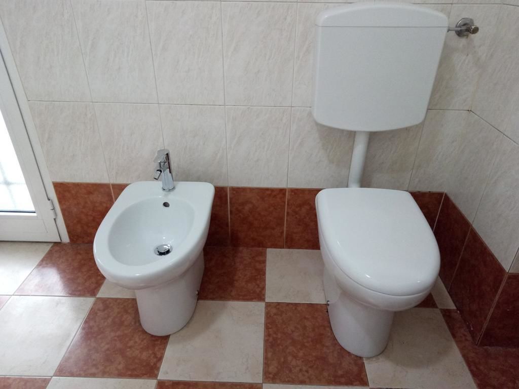 Un bagno con bidet, WC e pavimento piastrellato.
