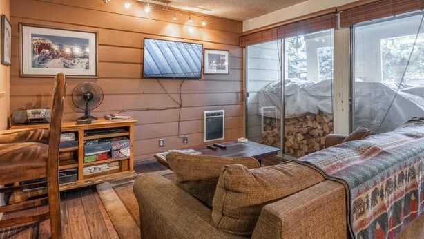 A cozy living room with a sofa, a wooden entertainment unit with a TV, and a fireplace. - Cozy Mammoth Studio – Fireplace, Pets Welcome (Mammoth Lakes)