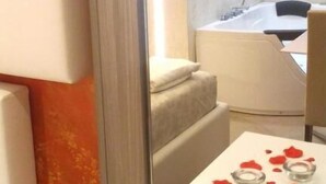 Een moderne badkamer met een badkuip, een spiegel en een tafeltje met rozenblaadjes en glazen.