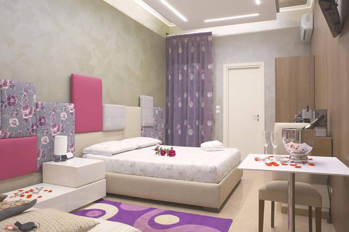 Ein modernes Schlafzimmer mit Bett, Nachttischen, einem Schreibtisch und einem Sessel.