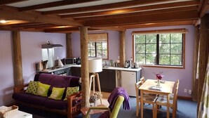A cozy cabin interior with a sofa, dining table, and kitchenette. - Charming Holiday Hideaway near the Lake (Lake Okareka)
