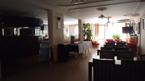 A spacious living room with a dining area, a television, and a large window providing natural light. - Hotel Ozkar (Mersin)