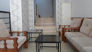 A living room with two sofas, a coffee table, and a staircase leading to an upper floor. - Hotel Ozkar (Mersin)