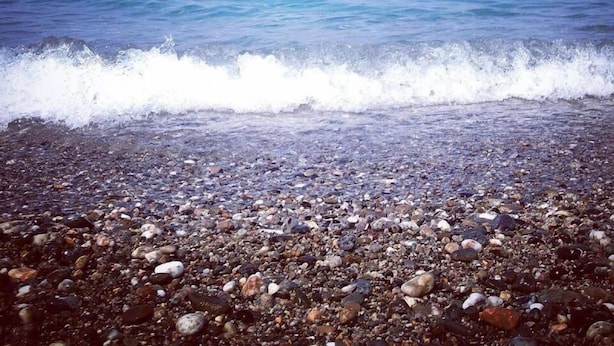 Una playa de guijarros con olas rompiendo en la orilla.