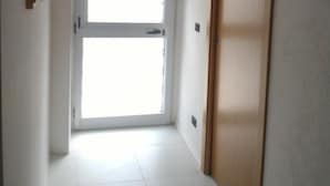Un pasillo con un ventanal grande, una puerta de madera y un equipo de aire acondicionado instalado en el techo.