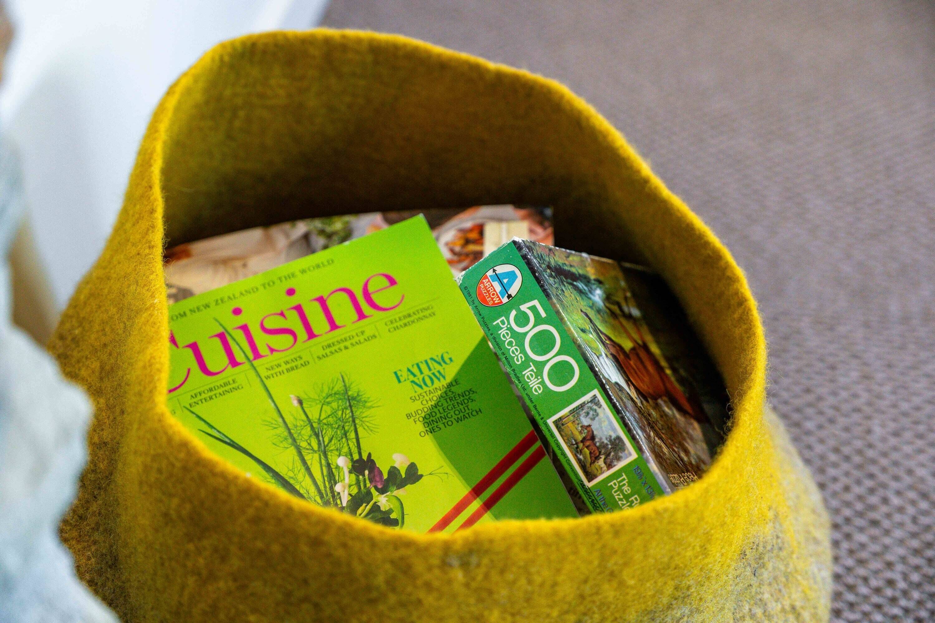 A yellow felt bag filled with magazines.