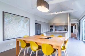 A modern kitchen with a central island, a dining area with a large wooden table and yellow chairs, and a large map on the wall.