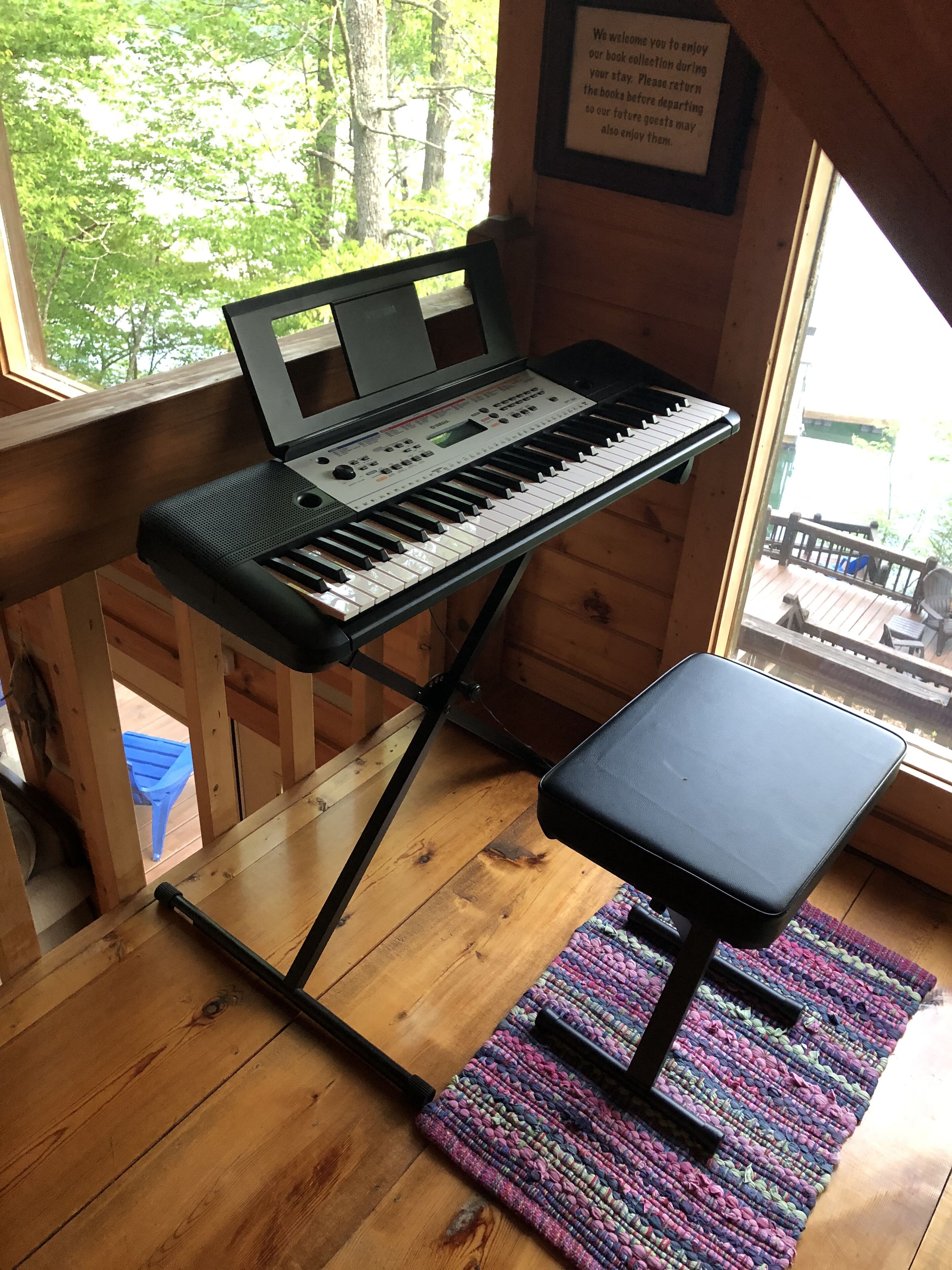 Un teclado sobre un atril en una habitación con paredes de madera y una ventana.